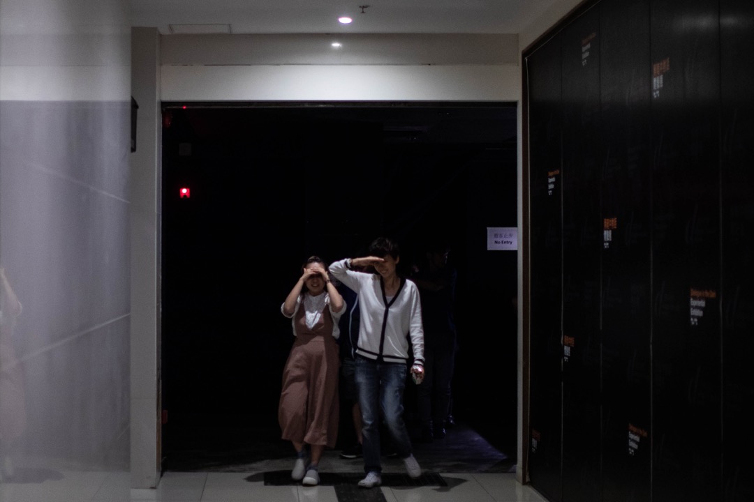 完成75分鐘的黑暗旅程後,體驗者尚未適應「光明」,用手半遮住眼睛。