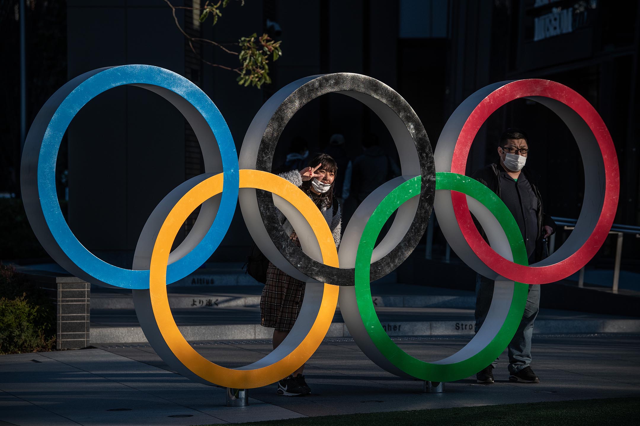 2020年3月24日日本東京，戴著口罩的人們在奧運五環旁拍照。