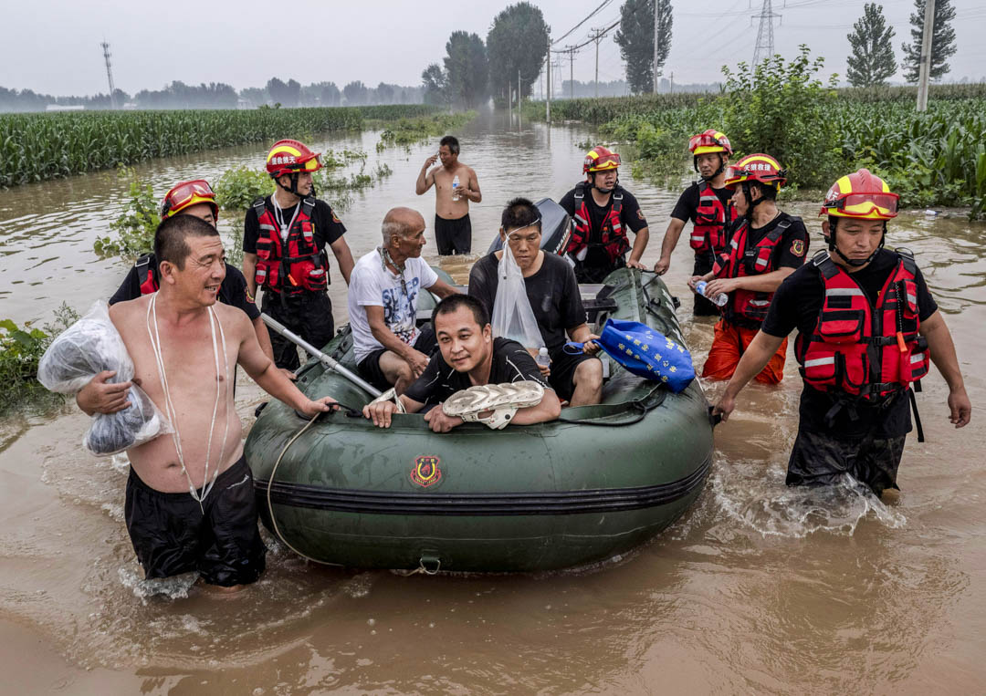 2023年8月3日，中国河北涿州附近被洪水淹没的地区，救援人员帮助当地居民以船安全抵达安全地带。摄：Kevin Frayer/Getty Images
